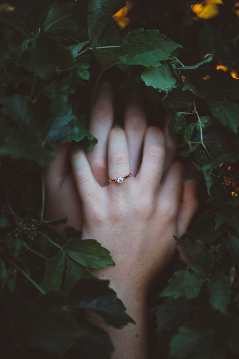 預約 1 - soulterfly.com gold-colored ring on hands surrounded by green leaves