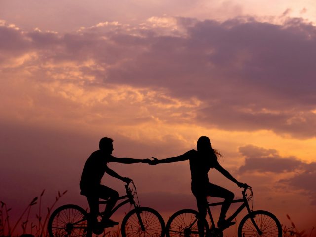 Photo by Everton Vila woman on bike reaching for man's hand behind her also on bike
